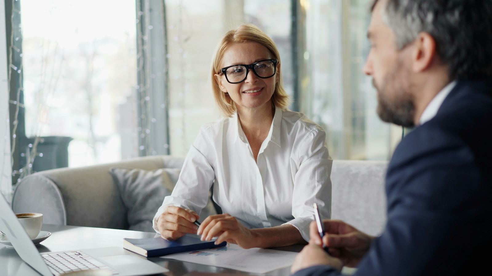 Una asesora sonriente conversa con un cliente en una oficina luminosa