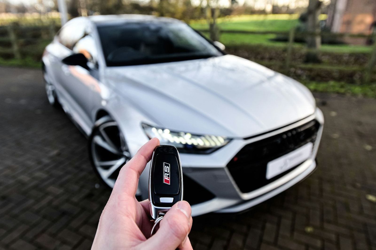 Una mano entrega la llave de un auto plateado